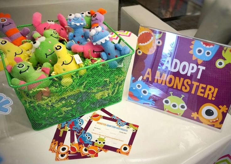 there are many stuffed animals in the basket on the table and next to it is a book about adopt a monster