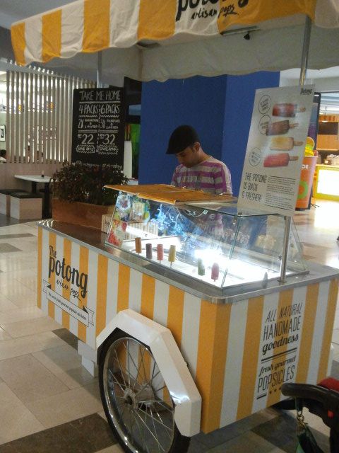 a man standing behind a food cart with donuts on it