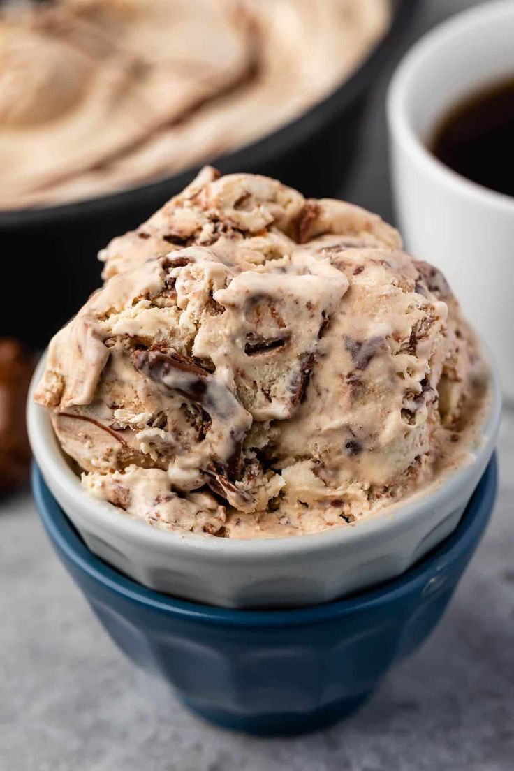 a bowl filled with ice cream next to two cups of coffee