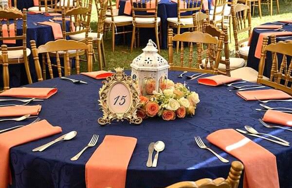 the table is set for an event with orange and blue linens