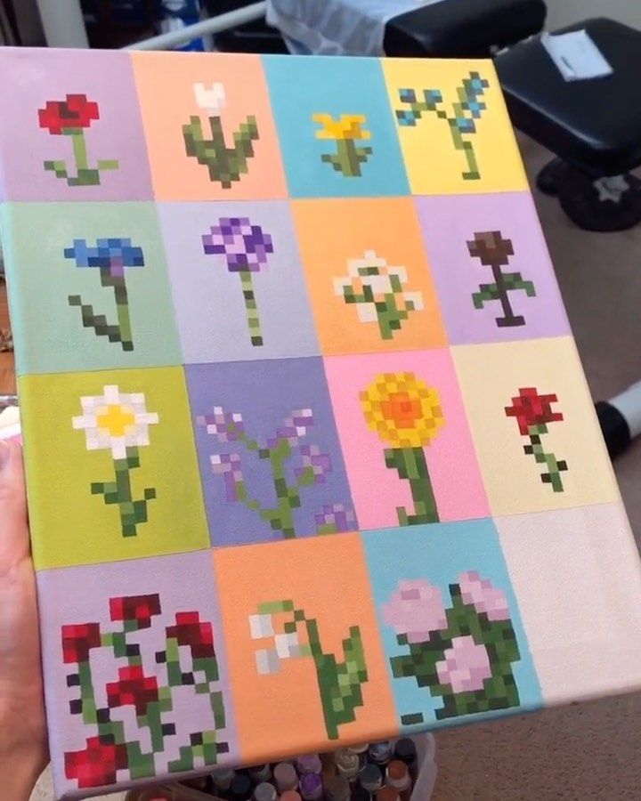 a person holding up a piece of art made out of squares with flowers on them