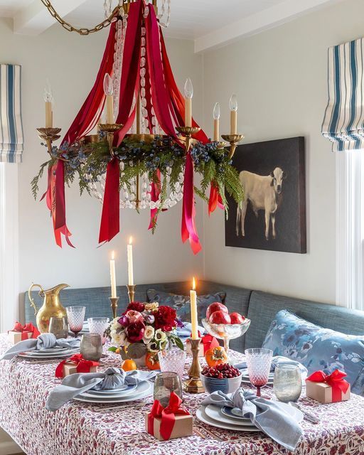 a dining room table set for christmas with red bows and candles on top of it