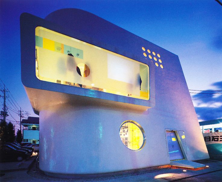 an unusual building with two round windows on the front and one in the back that is lit up at night