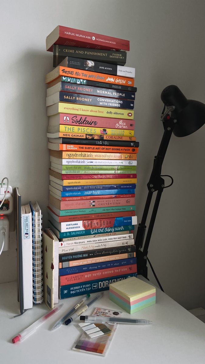 a stack of books sitting on top of a table next to a lamp and other items