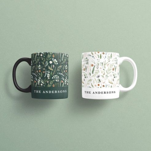 two coffee mugs sitting next to each other on a green surface with the words the andersons printed on them