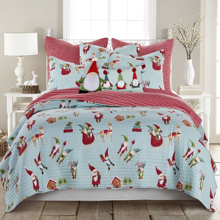 a bed covered in a blue and red comforter with santa clauss on it