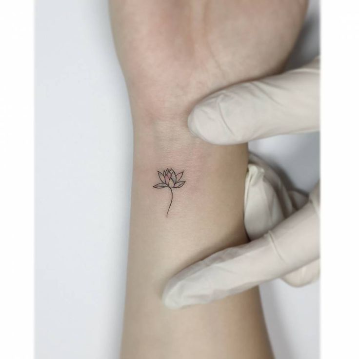 a woman's wrist with a small flower tattoo on the left side of her arm