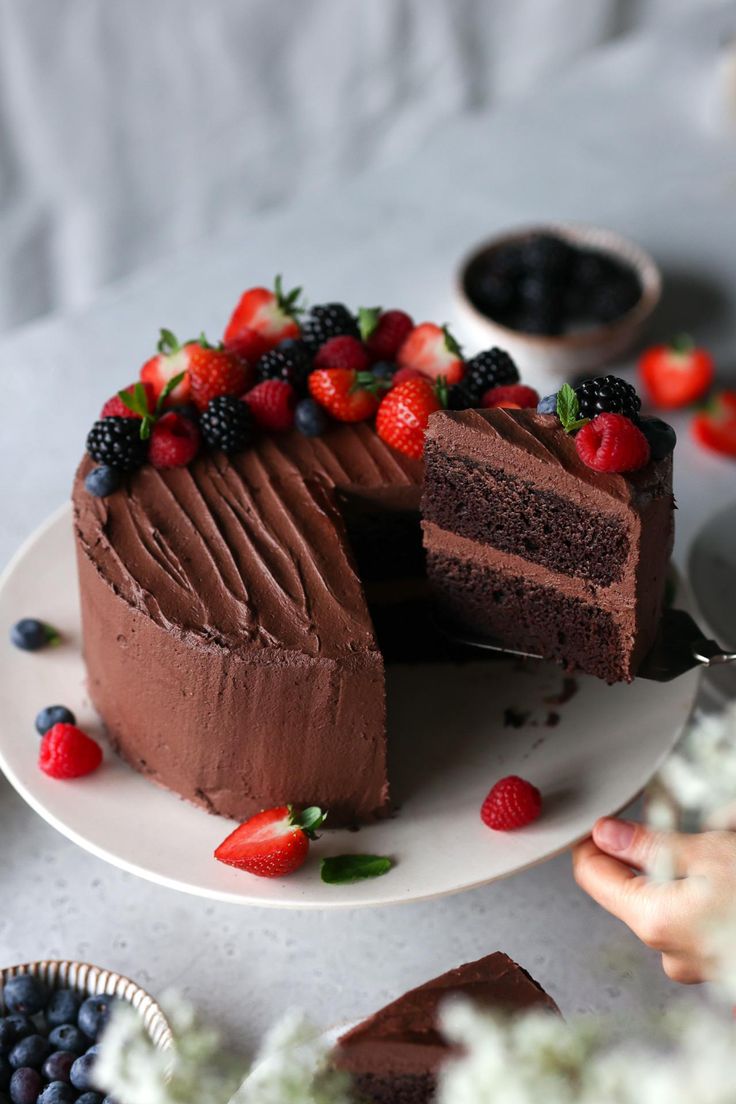 a chocolate cake with berries on the top and one slice cut out to show it's filling