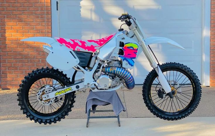 a dirt bike parked on top of a metal step stool in front of a garage