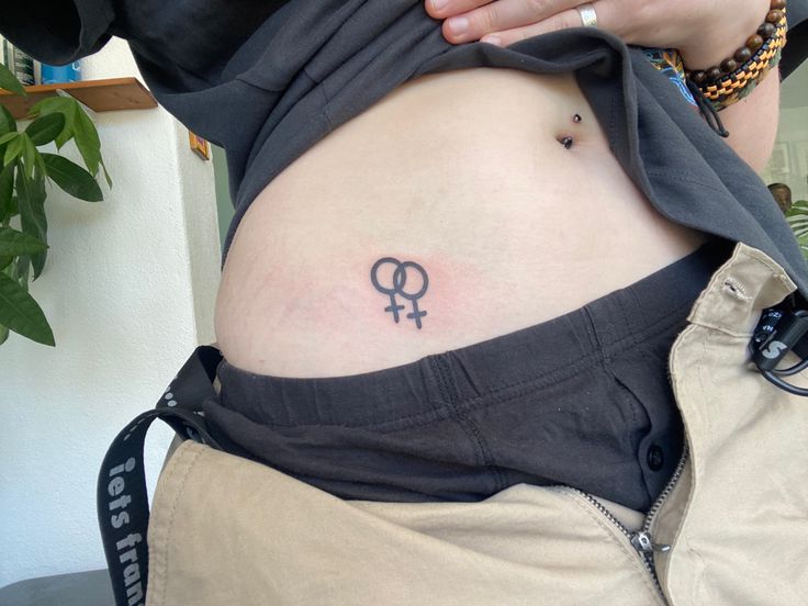 a woman with a tattoo on her stomach is holding onto the side of her belly