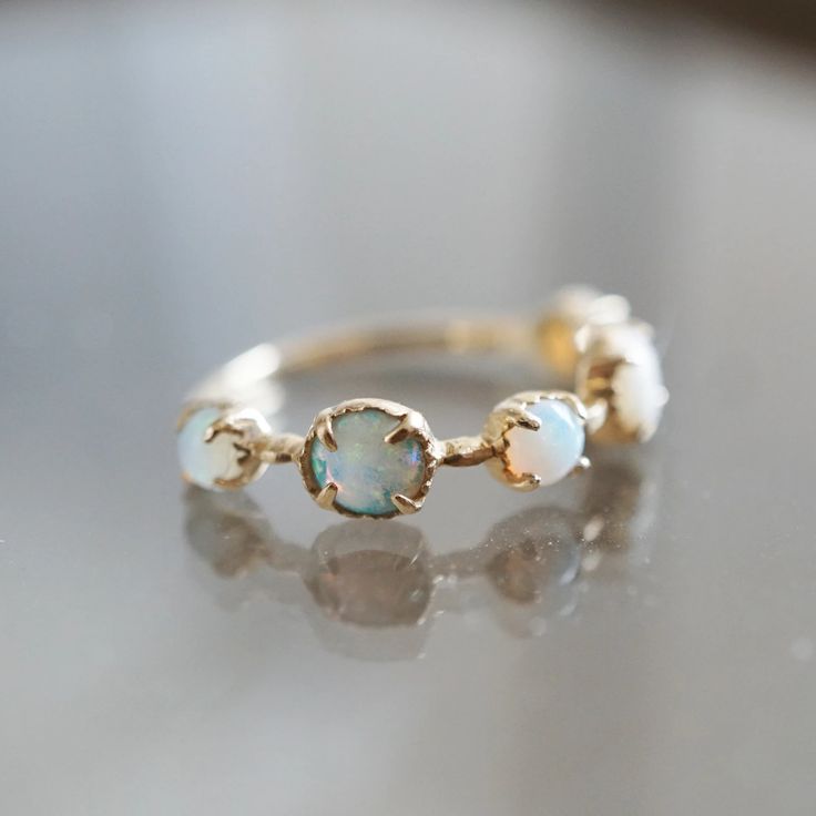 a gold ring with three opal stones on the front and side, sitting on top of a table