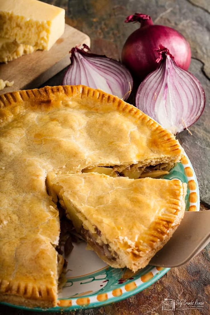 a pie on a plate with some onions next to it