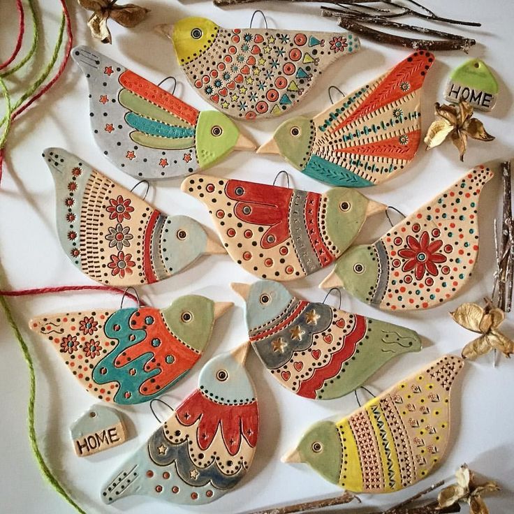 ceramic bird ornaments are displayed on a white surface with red and green string, along with twine