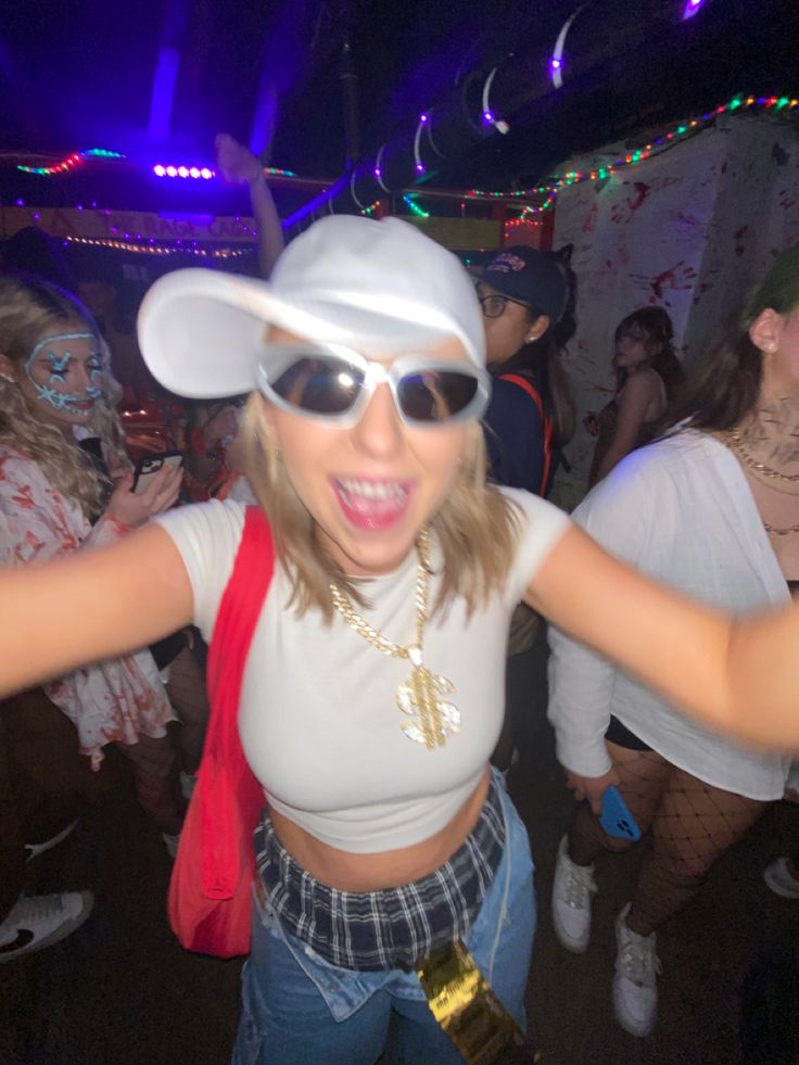 a woman wearing sunglasses and a white hat is dancing in a club with other people