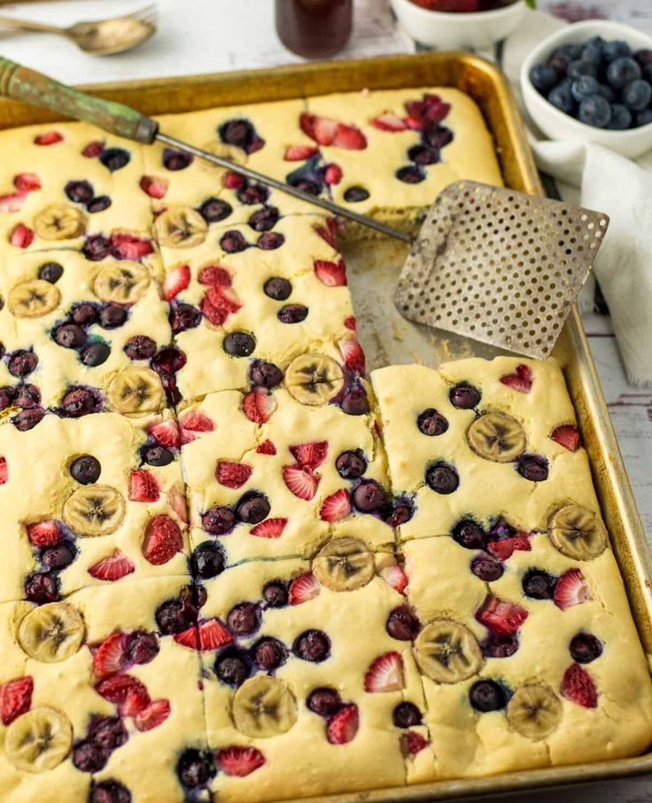 blueberries, strawberries and bananas are arranged on top of a sheet of cake