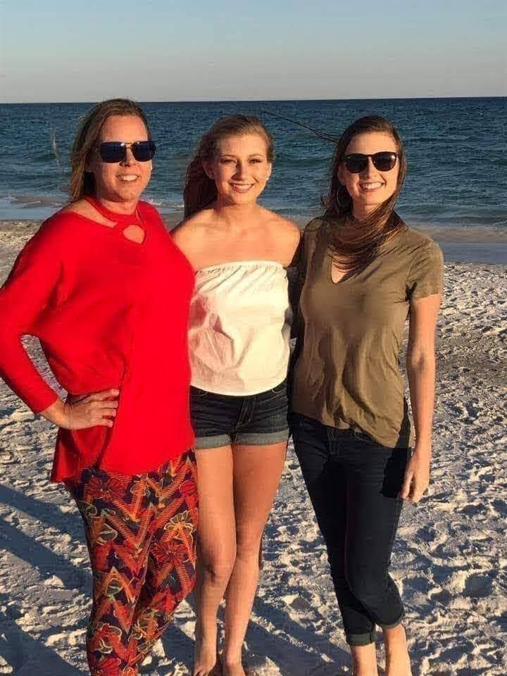 three women are standing on the beach together