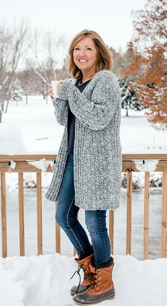 a woman standing in the snow holding a cup