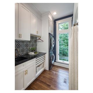 a kitchen with white cabinets and black counter tops next to an open door that leads out onto a wooded area