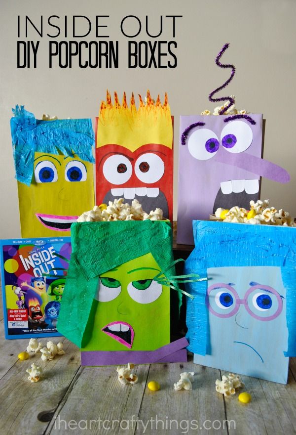 some paper bags that have faces on them and popcorn in the bag is next to each other