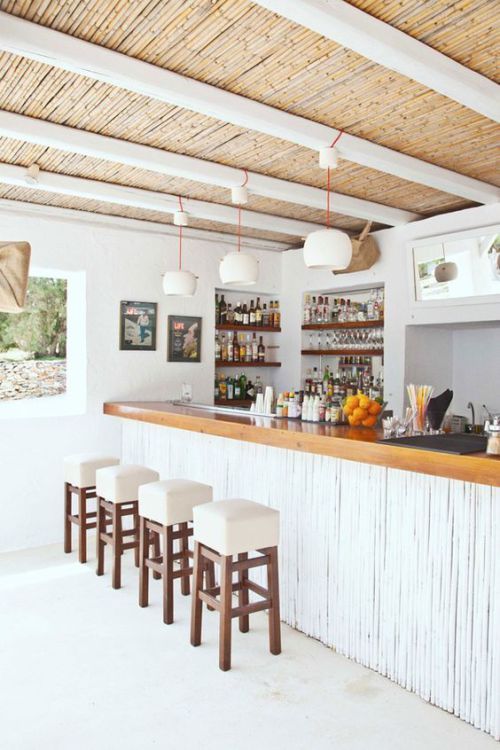 a bar with stools and bottles on the counter in a room that has white walls