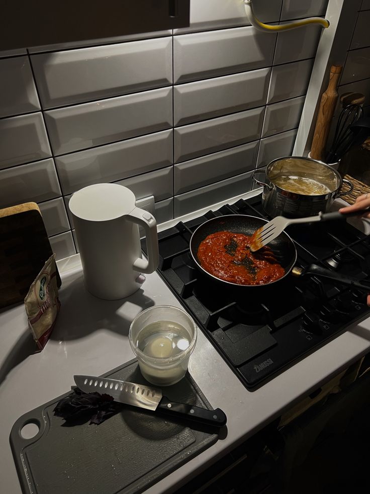 a person is cooking food on the stove with a spatula and sauce in front of them