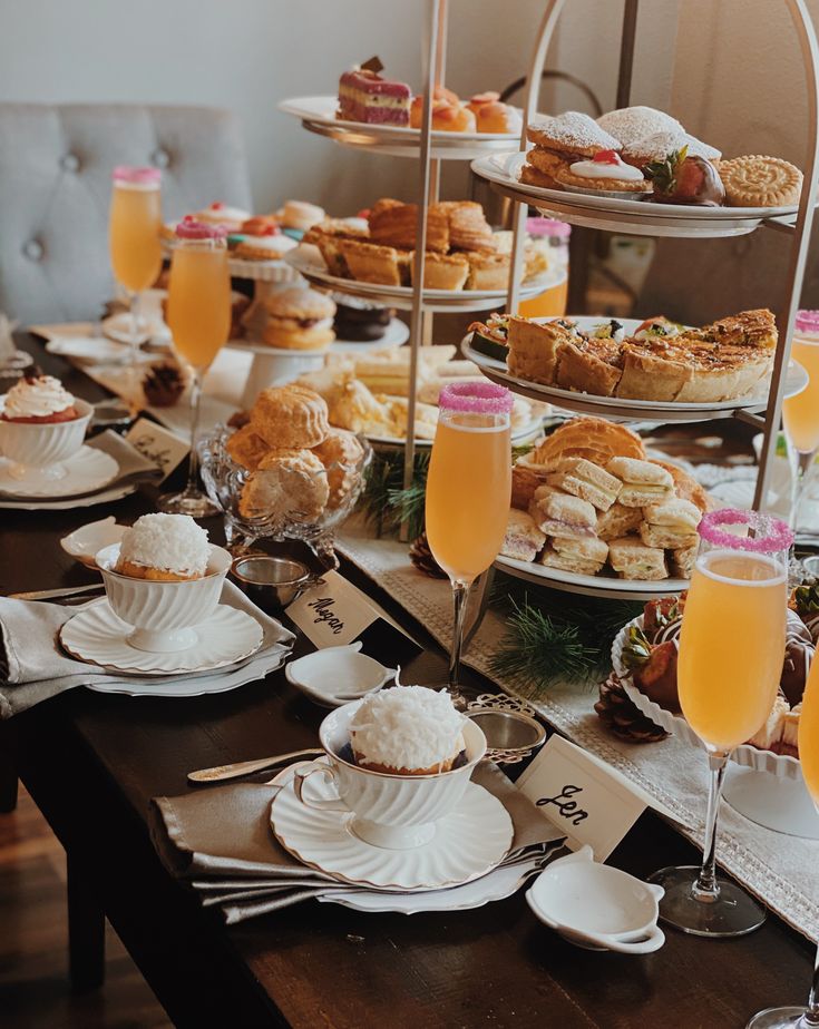 an assortment of pastries and desserts are on display at a table with wine glasses