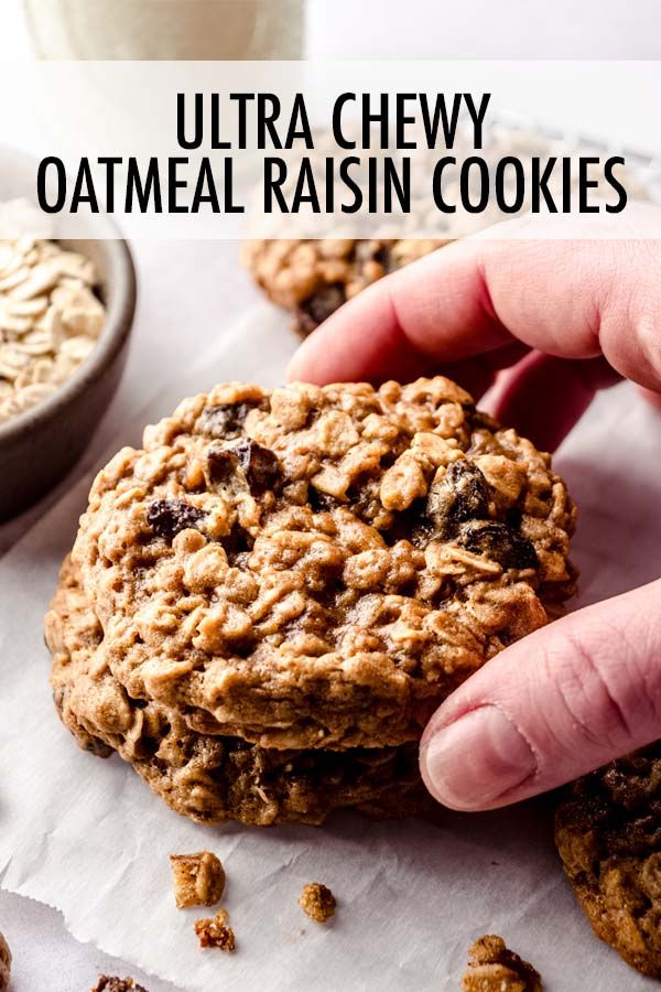 a hand is picking up an oatmeal raisin cookie