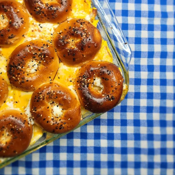 a casserole dish with bagels and cheese in it on a blue checkered table cloth