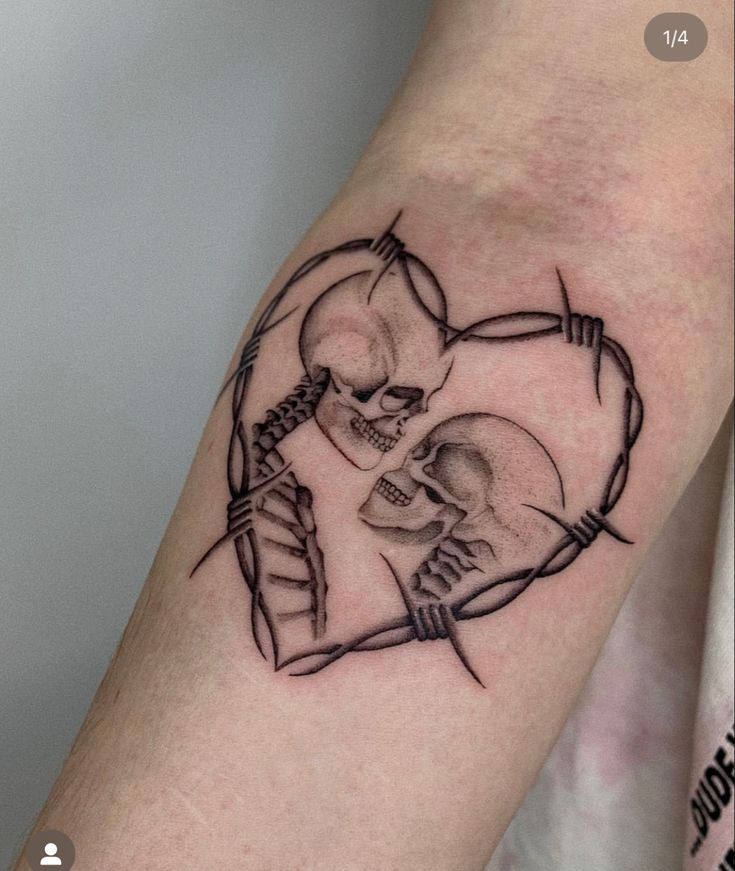 a couple of skulls in the shape of a heart with barbed wire on their arm