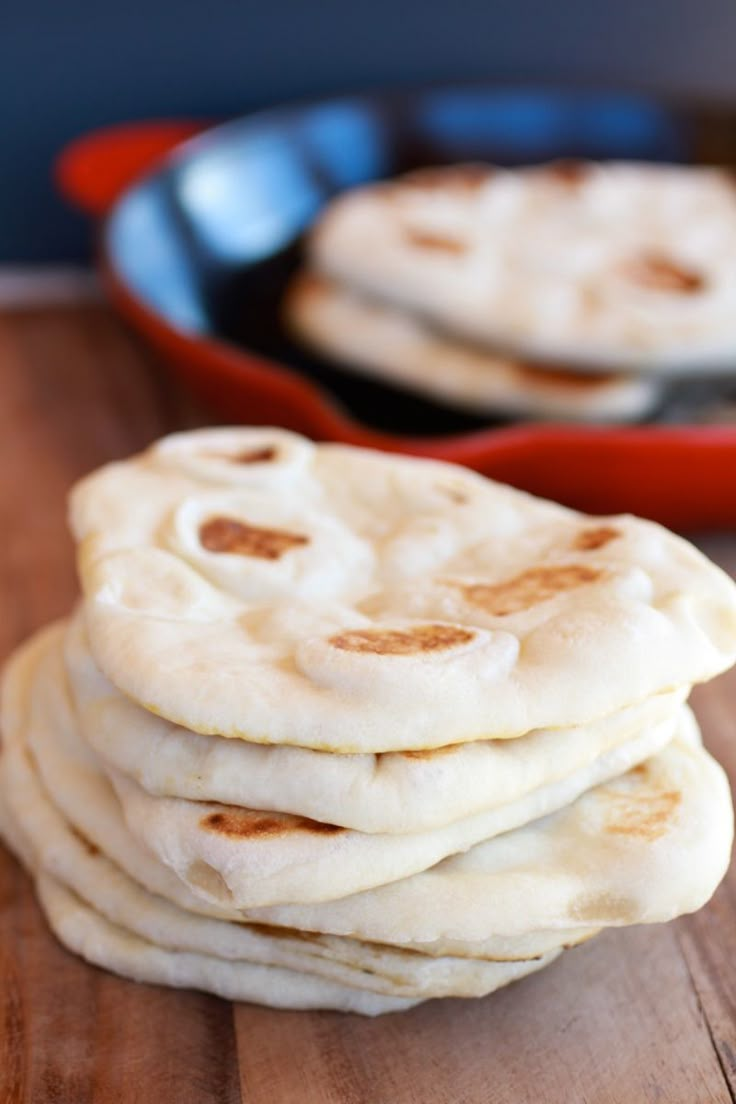 several flat breads are stacked on a wooden table