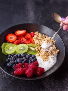 a bowl filled with yogurt, berries, kiwis and granola