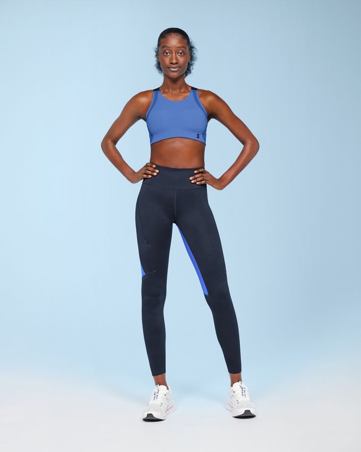 a woman in blue sports bra top and black leggings posing for the camera