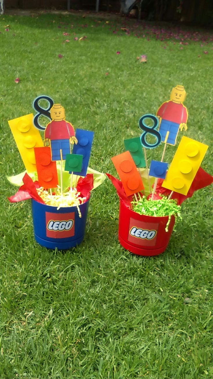 two buckets filled with lego blocks on top of a grass covered field next to each other