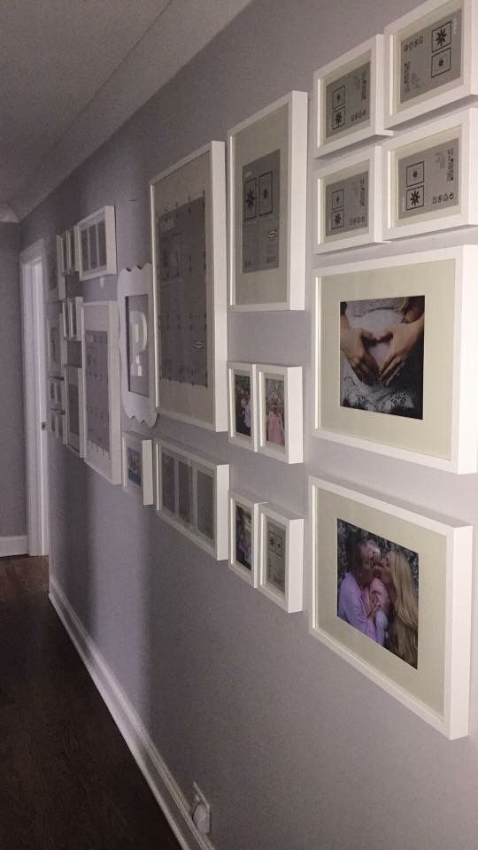 a wall with many pictures on it in a hallway next to a door and window