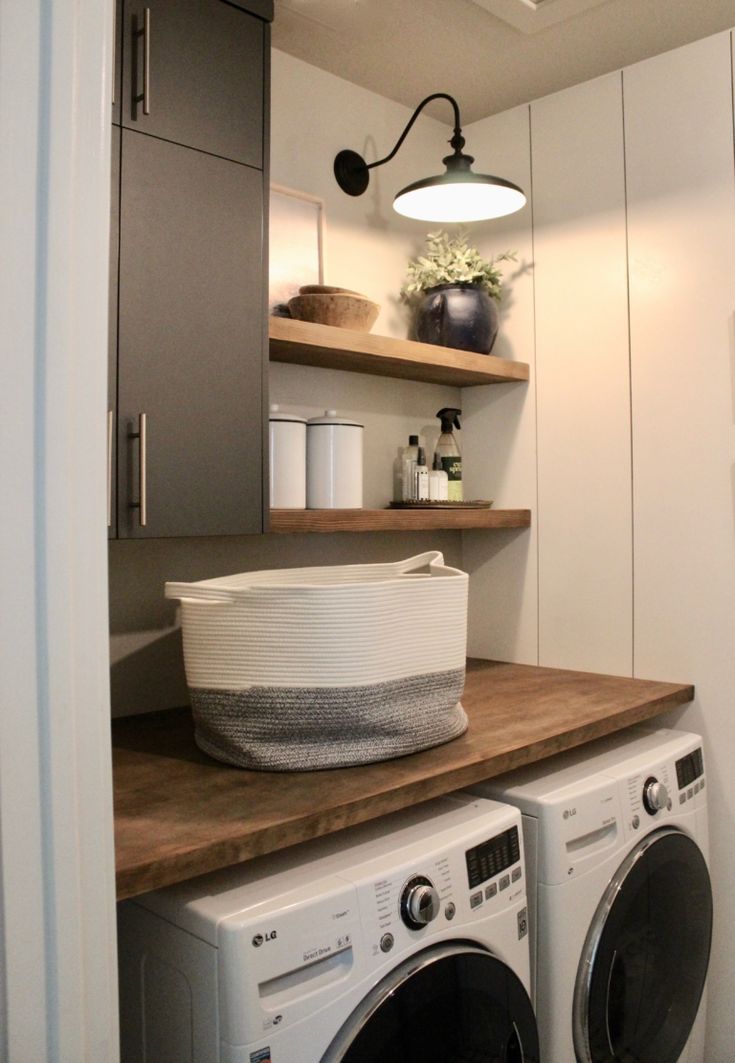 a washer and dryer in a small room with shelves on the wall behind them