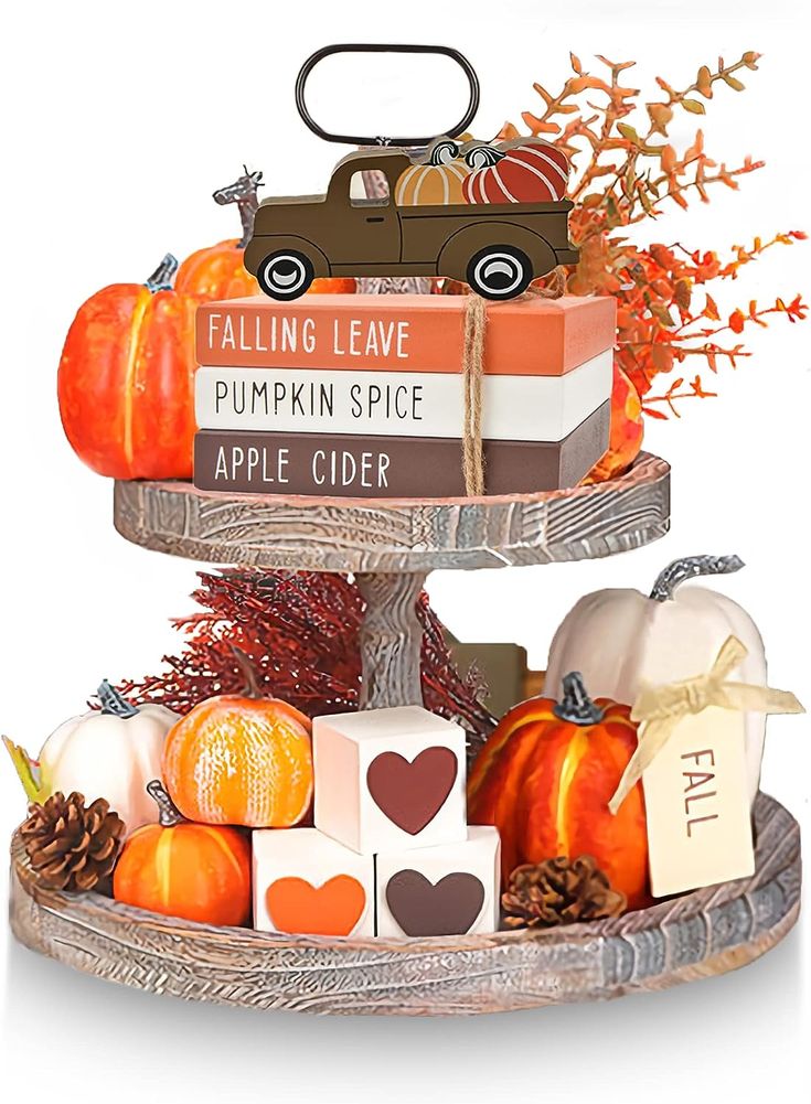 a three tiered tray with pumpkins, candles and other fall decorations on it