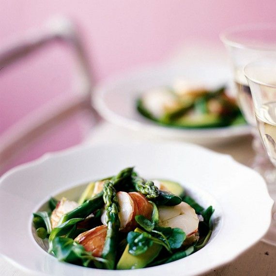 a white plate topped with asparagus and scallops next to a glass of water