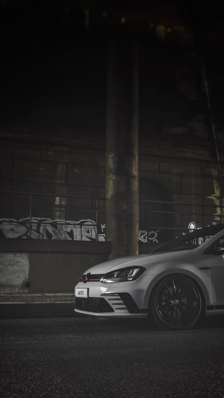 a silver car parked in front of a building with graffiti on the side of it