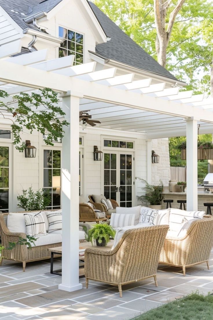 a covered patio with wicker furniture and potted plants