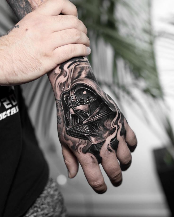 a man with a tattoo on his arm and hand is holding a darth vader