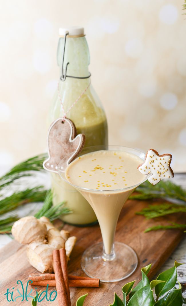 a drink in a glass on a cutting board next to some spices and ginger sticks