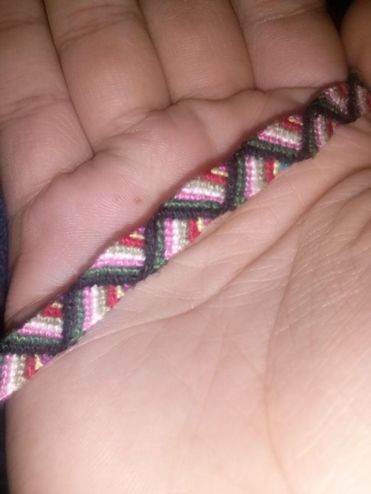 a hand holding a small braided object in it's palm