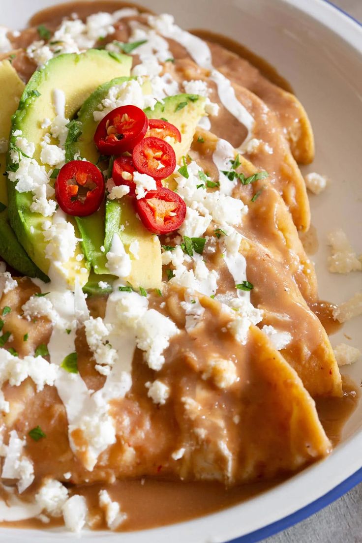 an enchilada dish with tomatoes, avocado and feta cheese