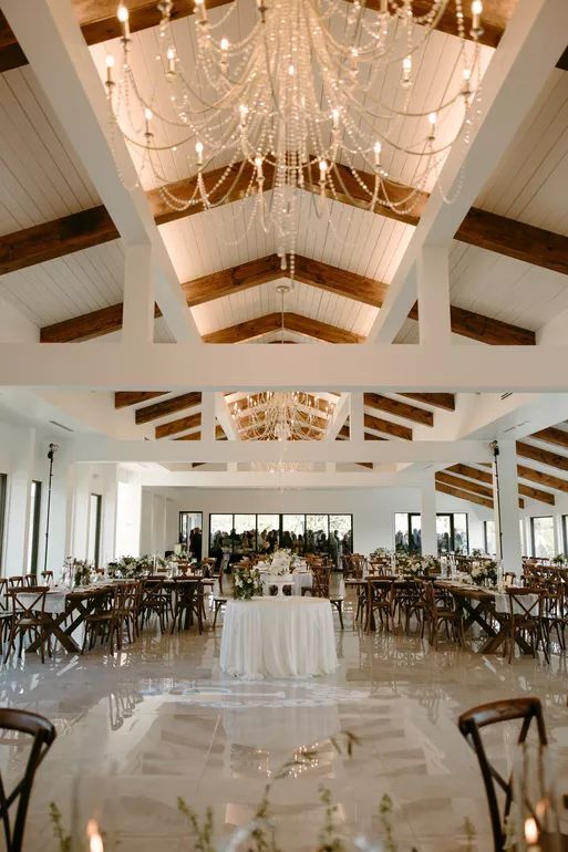 a large room with tables and chandeliers hanging from the ceiling