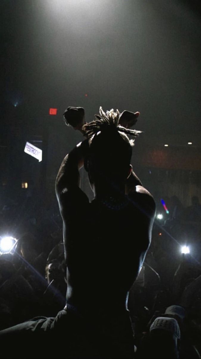 a person standing in front of a crowd at a concert with their hands on their head