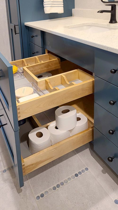 two rolls of toilet paper are stored in the drawer on the bathroom sink countertop