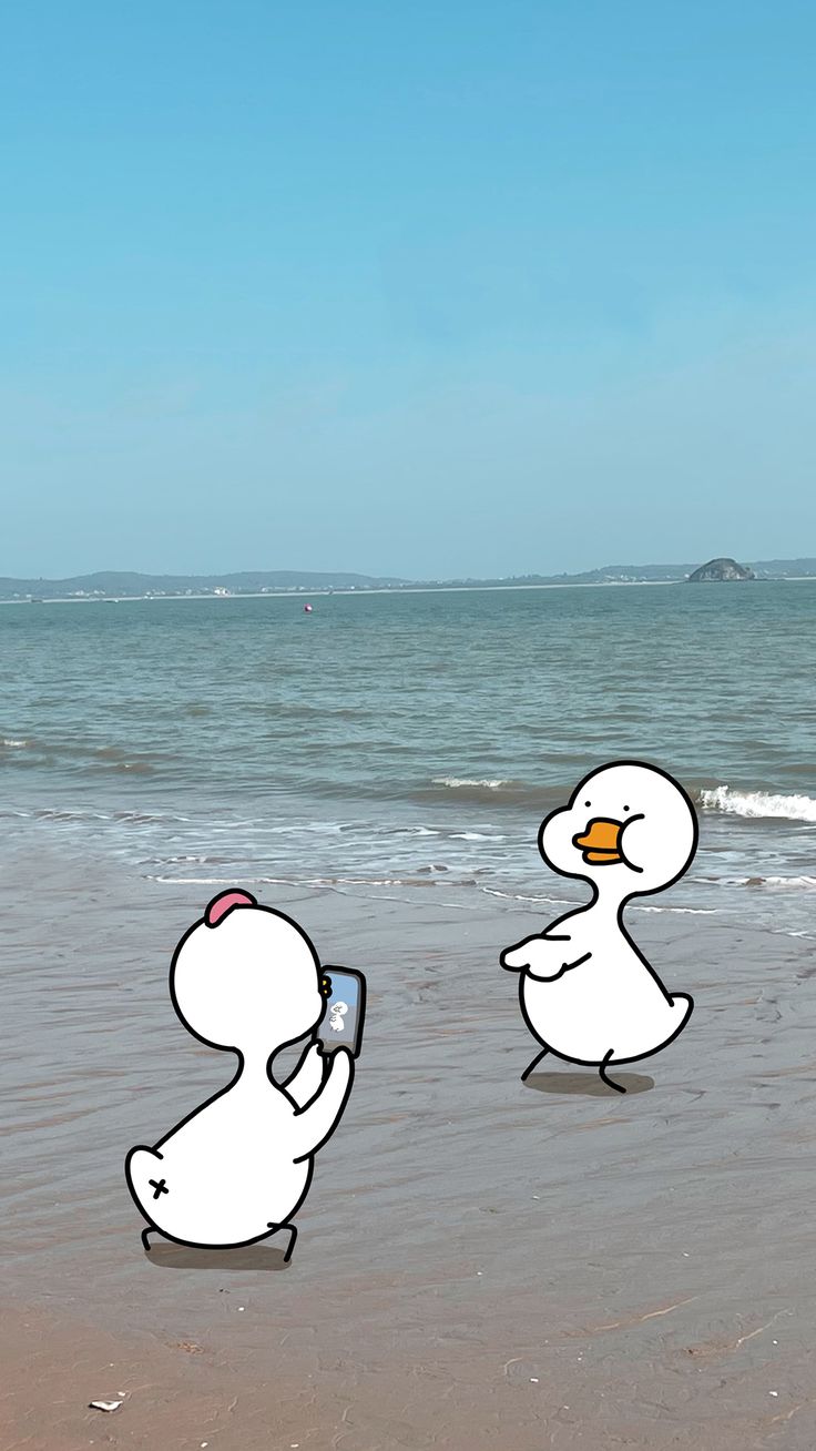 two white ducks are on the beach and one is holding a cell phone in its hand