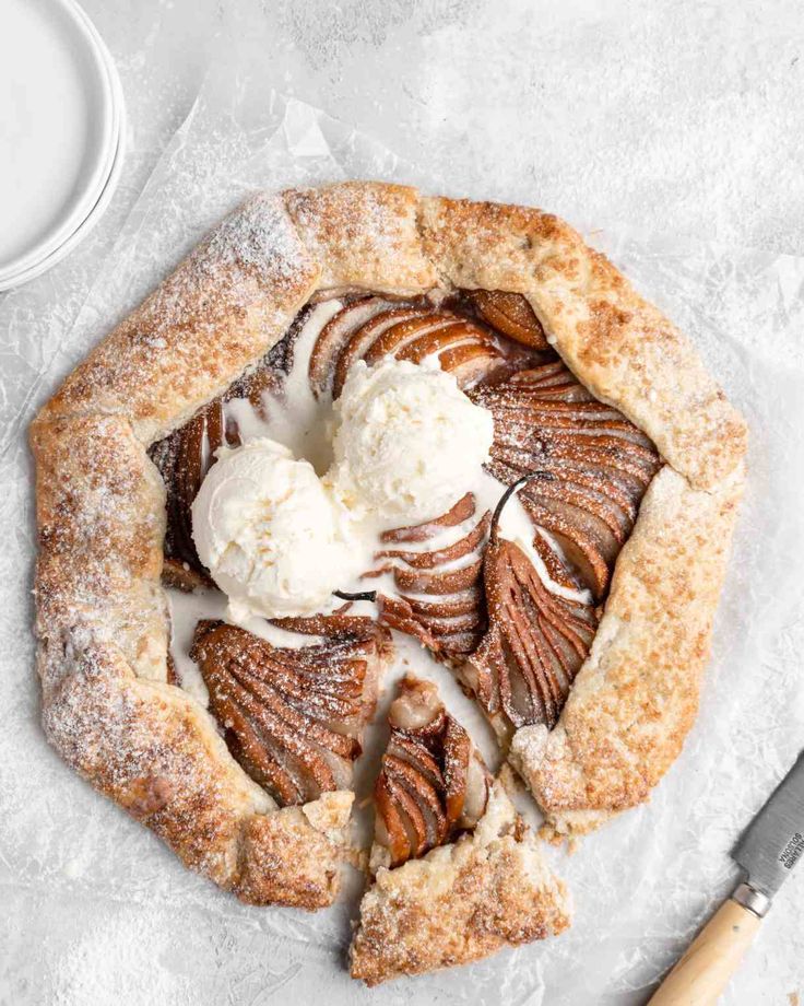 a pastry with ice cream on top and cinnamon swirl around the edges sitting on wax paper next to a knife