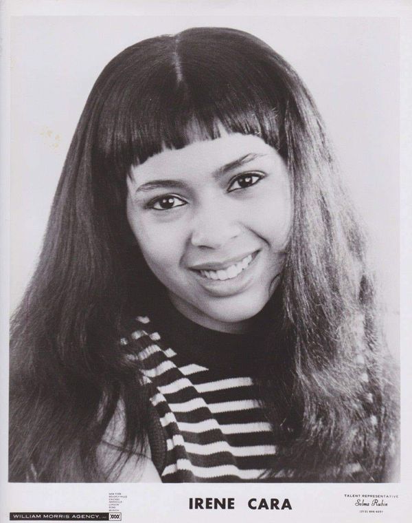 an old black and white photo of a woman with long hair smiling at the camera