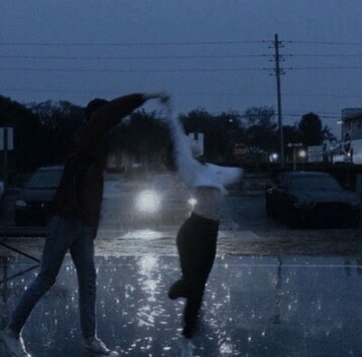 two people dancing in the rain at night